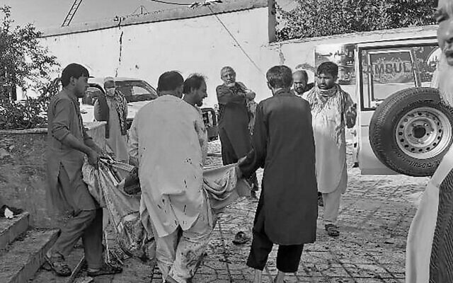 EDITORS NOTE: Graphic content / Afghan men carry the dead body of a victim to an ambulance after a bomb attack at a mosque in Kunduz on October 8, 2021. (Photo by - / AFP)